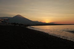 Romantic sunset on the sea coast in Indonesia. Surfer goes to enjoy paddleboard at sunset.Coastline panorama with majestic volcano royalty free stock images Romantic sunset on the sea coast in Indonesia. Surfer goes to enjoy paddleboard at sunset.Coastline panorama with majestic volcano royalty free stock images