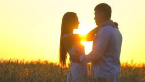 Romantic young happy couple silhouette in golden wheat field at sunset. Woman and man hugging and kissing against stock footage Romantic young happy couple silhouette in golden wheat field at sunset. Woman and man hugging and kissing against stock footage
