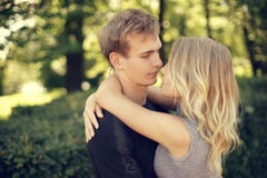 Romantische Paare, die im Park an einem Sommertag umarmen lizenzfreies stockbild Romantische Paare, die im Park an einem Sommertag umarmen lizenzfreies stockbild