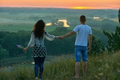 Romantische paargang op heuvel bij zonsondergang op land openlucht, meisje met boeket van wilde bloem, mooi landschap en heldere Royalty-vrije Stock Foto's Romantische paargang op heuvel bij zonsondergang op land openlucht, meisje met boeket van wilde bloem, mooi landschap en heldere Royalty-vrije Stock Foto's