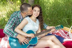 Romantisches Picknick des Sommers Kerl zeigt dem Mädchen, wie man die Gitarre spielt Paare, die auf dem Gras sitzen stockfotografie Romantisches Picknick des Sommers Kerl zeigt dem Mädchen, wie man die Gitarre spielt Paare, die auf dem Gras sitzen stockfotografie