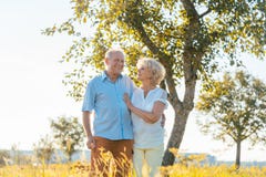 Romantisches älteres Paarhändchenhalten beim in die Landschaft zusammen gehen stockfotografie Romantisches älteres Paarhändchenhalten beim in die Landschaft zusammen gehen stockfotografie