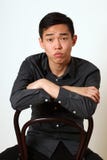 Romantiskt ungt asiatiskt mansammanträde på en stol royaltyfria bilder Romantiskt ungt asiatiskt mansammanträde på en stol royaltyfria bilder