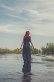 Roodharige vrouw die in de rivier lopen stock afbeelding Roodharige vrouw die in de rivier lopen stock afbeelding