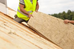 Rooferbyggmästarearbetare som installerar takisoleringsmaterial på nytt hus under konstruktion fotografering för bildbyråer Rooferbyggmästarearbetare som installerar takisoleringsmaterial på nytt hus under konstruktion fotografering för bildbyråer