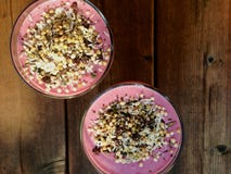 Rosa Smoothies mit rohem Granola des strengen Vegetariers des Buchweizens auf sonniger Plattform lizenzfreies stockbild Rosa Smoothies mit rohem Granola des strengen Vegetariers des Buchweizens auf sonniger Plattform lizenzfreies stockbild