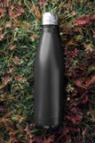 Rostfreie Flaschenthermosflasche, schwarze Farbe Auf dem Hintergrund des grünen Grases lizenzfreie stockfotografie Rostfreie Flaschenthermosflasche, schwarze Farbe Auf dem Hintergrund des grünen Grases lizenzfreie stockfotografie