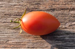 Rot-orange, kleine Tomate auf einem hölzernen Hintergrund stockbild Rot-orange, kleine Tomate auf einem hölzernen Hintergrund stockbild
