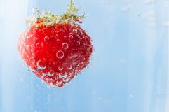 Rote Erdbeere, die in Blasen des funkelnden blauen Wassers schwimmt stockfoto Rote Erdbeere, die in Blasen des funkelnden blauen Wassers schwimmt stockfoto
