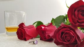 Rote Rosen auf weißer Tabelle nahe silbernem Ring mit großem violettem Kristall stockfoto Rote Rosen auf weißer Tabelle nahe silbernem Ring mit großem violettem Kristall stockfoto