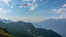 Roter Gleitschirm im blauen bewölkten Himmel über grünen Bergen Grünes Tal mit Drahtseilbahn unten unten Krasnaya Polyana, Sochi lizenzfreies stockbild Roter Gleitschirm im blauen bewölkten Himmel über grünen Bergen Grünes Tal mit Drahtseilbahn unten unten Krasnaya Polyana, Sochi lizenzfreies stockbild
