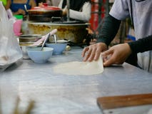 Roti dough being stretched and slapped into a sheet before being fried in hot griddle stock image Roti dough being stretched and slapped into a sheet before being fried in hot griddle stock image