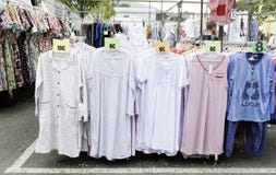 A roupa está em um mercado de rua com uma grande amostra de camisetas foto de stock royalty free A roupa está em um mercado de rua com uma grande amostra de camisetas foto de stock royalty free