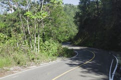 Route rurale pour descendre la montagne entourée par la verdure luxuriante photographie stock Route rurale pour descendre la montagne entourée par la verdure luxuriante photographie stock