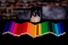 A row of colored pencils lined up in a wavy pattern with a blurry background and an electirc pencil sharpener full stock images A row of colored pencils lined up in a wavy pattern with a blurry background and an electirc pencil sharpener full stock images