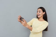 Rozochocona piękna młoda kobieta bawić się wideo gry na telefonie komórkowym zdjęcia stock Rozochocona piękna młoda kobieta bawić się wideo gry na telefonie komórkowym zdjęcia stock