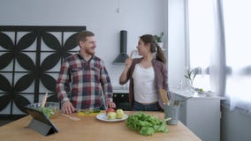 Rozochocona rodzina atrakcyjna żona z męża tanem i mieć zabawa, podczas gdy gotujący zdrowego posiłek od warzyw dalej zbiory wideo Rozochocona rodzina atrakcyjna żona z męża tanem i mieć zabawa, podczas gdy gotujący zdrowego posiłek od warzyw dalej zbiory wideo