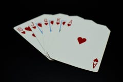Rubor recto de la escalera real de las tarjetas de los corazones en juego de póker contra fondo negro imagen de archivo libre de regalías Rubor recto de la escalera real de las tarjetas de los corazones en juego de póker contra fondo negro imagen de archivo libre de regalías