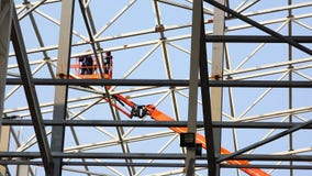 Ruch pracownicy przy wzrostem w dźwignięciu między strukturami metal Ruch pracownicy przy wzrostem w dźwignięciu między strukturami metal