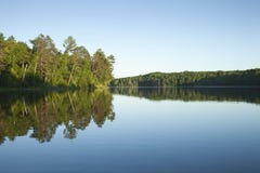 Ruhiger Nordminnesota See mit Kiefern bei Sonnenuntergang auf einem clea lizenzfreie stockfotos Ruhiger Nordminnesota See mit Kiefern bei Sonnenuntergang auf einem clea lizenzfreie stockfotos