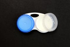 Runde Beh?lter f?r die wei?en und blauen Linsen auf einem schwarzen Hintergrund lizenzfreies stockbild Runde Beh?lter f?r die wei?en und blauen Linsen auf einem schwarzen Hintergrund lizenzfreies stockbild