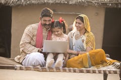 Rural Indian family using laptop on traditional bed at village royalty free stock photography Rural Indian family using laptop on traditional bed at village royalty free stock photography