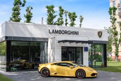 RUSIA, MOSCÚ - 30 de junio de 2017: Salón del automóvil de Lamborghini al lado de Lamborghini amarillo en un fondo hermoso del ci imágenes de archivo libres de regalías RUSIA, MOSCÚ - 30 de junio de 2017: Salón del automóvil de Lamborghini al lado de Lamborghini amarillo en un fondo hermoso del ci imágenes de archivo libres de regalías