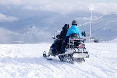 People in professional gear ride from the top of the mountain on a snowmobile to the mountain to ride snowboard freeride. Concep stock images People in professional gear ride from the top of the mountain on a snowmobile to the mountain to ride snowboard freeride. Concep stock images