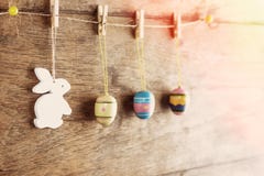 Rustic Easter background: Vintage painted eggs and white bunny hang on clothespins against old brown wooden wall. Holiday concept Royalty Free Stock Photo Rustic Easter background: Vintage painted eggs and white bunny hang on clothespins against old brown wooden wall. Holiday concept Royalty Free Stock Photo