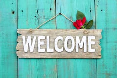 Rustic welcome sign with red flower hanging on distressed antique green door