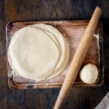 Ruw vers deeg op een houten raad met deegrol stock fotografie Ruw vers deeg op een houten raad met deegrol stock fotografie