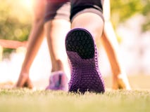 Réguliers prêts disparaissent Plan rapproché des chaussures de course sur l'herbe, la jeune dame sur la position de début et alle Photo stock Réguliers prêts disparaissent Plan rapproché des chaussures de course sur l'herbe, la jeune dame sur la position de début et alle Photo stock