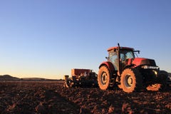 Röd traktor i öppet fält med planteren royaltyfri fotografi Röd traktor i öppet fält med planteren royaltyfri fotografi