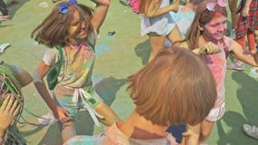 RÚSSIA, IRKUTSK - 27 DE JUNHO DE 2018: Jovens felizes que dançam e que comemoram durante o festival de Holi das cores Multidão de RÚSSIA, IRKUTSK - 27 DE JUNHO DE 2018: Jovens felizes que dançam e que comemoram durante o festival de Holi das cores Multidão de