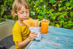 S?t liten caucasian pojke som ?ter pannkakor och dricker orange fruktsaft fotografering för bildbyråer S?t liten caucasian pojke som ?ter pannkakor och dricker orange fruktsaft fotografering för bildbyråer