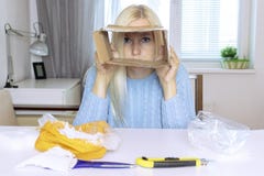 Sad blond woman sitting by the table after unboxing a parcel and looking through the empty box, all objects on the table are in me royalty free stock photos Sad blond woman sitting by the table after unboxing a parcel and looking through the empty box, all objects on the table are in me royalty free stock photos