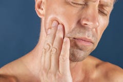Sad depressed man in pain holding his cheek. Portrait of a man on blue background. emotion facial expression. feelings royalty free stock photography Sad depressed man in pain holding his cheek. Portrait of a man on blue background. emotion facial expression. feelings royalty free stock photography