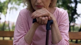 Sad grandmother leaning on walking stick sitting on bench in park, nursing home royalty free stock images Sad grandmother leaning on walking stick sitting on bench in park, nursing home royalty free stock images