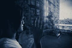 SAD kvinna som ut ser på fönster som regnar droppar arkivfoto SAD kvinna som ut ser på fönster som regnar droppar arkivfoto