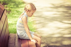 Sad little girl sitting on bench in the park Royalty Free Stock Images Sad little girl sitting on bench in the park Royalty Free Stock Images