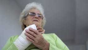 Sad senior woman having pain sitting and holding her injured hand in bandages stock image Sad senior woman having pain sitting and holding her injured hand in bandages stock image
