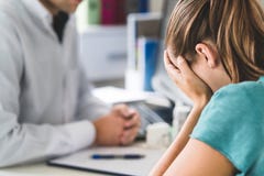 Sad patient visiting doctor. Young woman with stress or burnout getting help from medical professional or therapist. stock photography Sad patient visiting doctor. Young woman with stress or burnout getting help from medical professional or therapist. stock photography