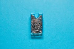 Safety pins in blue plastic box on blue background stock images Safety pins in blue plastic box on blue background stock images