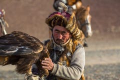 Berkutchi Eagle Hunter while hunting to the hare with a golden eagles on his arms in the mountains of Bayan-Olgii aimag. royalty free stock images Berkutchi Eagle Hunter while hunting to the hare with a golden eagles on his arms in the mountains of Bayan-Olgii aimag. royalty free stock images
