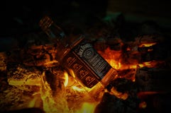 Bottle of whiskey Jack Daniel`s on fire with burning charcoals in the night stock images Bottle of whiskey Jack Daniel`s on fire with burning charcoals in the night stock images