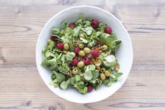 Salad of canons, raspberries, raisins, olives, nuts, carrots and pips on wooden background royalty free stock images Salad of canons, raspberries, raisins, olives, nuts, carrots and pips on wooden background royalty free stock images