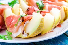 Salad of melon with thin slices of prosciutto, arugula leaves and balsamic sauce closeup stock photo Salad of melon with thin slices of prosciutto, arugula leaves and balsamic sauce closeup stock photo
