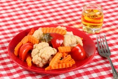 Salad of pickled vegetables cauliflower, paprika and carrot slices in a red plate and a glass of rakia grape, brandy like royalty free stock image Salad of pickled vegetables cauliflower, paprika and carrot slices in a red plate and a glass of rakia grape, brandy like royalty free stock image