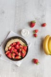 Salad of strawberries and banana on a dark plate on a light background. royalty free stock photography Salad of strawberries and banana on a dark plate on a light background. royalty free stock photography