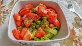 Salade de concombre et de tomate avec le poivre noir et les herbes, dans une cuvette en céramique blanche photographie stock libre de droits Salade de concombre et de tomate avec le poivre noir et les herbes, dans une cuvette en céramique blanche photographie stock libre de droits